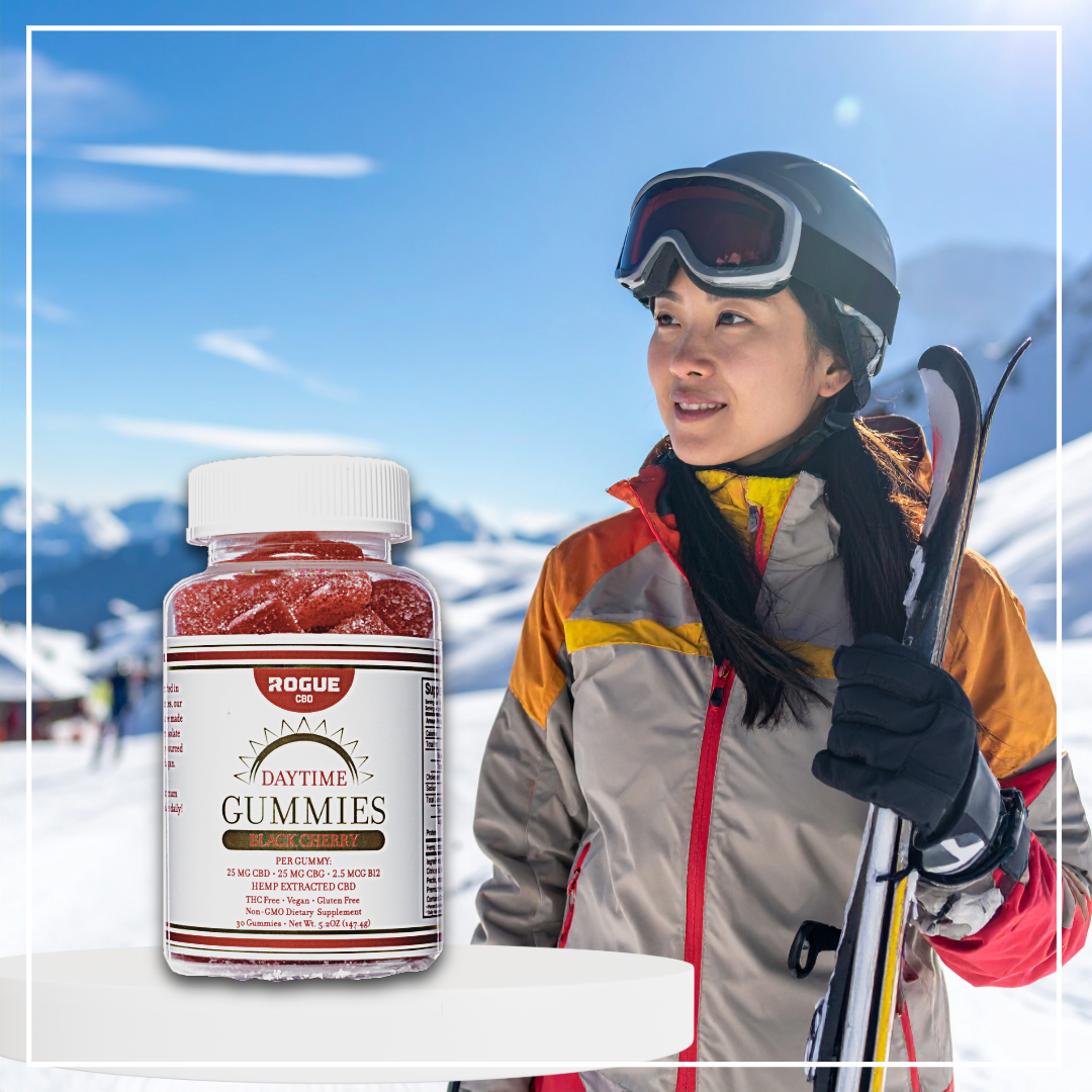 Person in ski gear with a bottle of Rogue Daytime Gummies in a snowy landscape